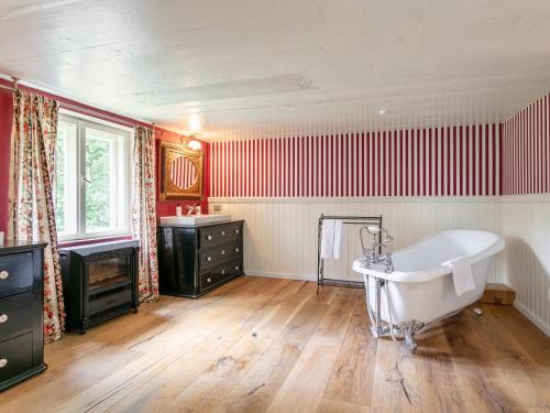 a bathroom with a white tub and red stripes at Waldhüsle in Dalaas
