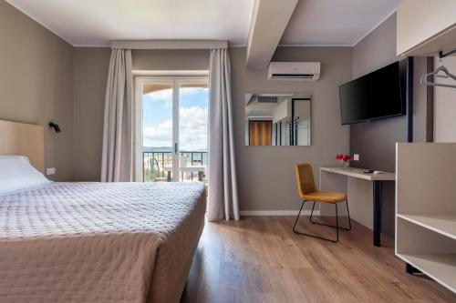 una camera da letto con un letto, una scrivania e una finestra di Hotel Pomara a San Michele di Ganzaria