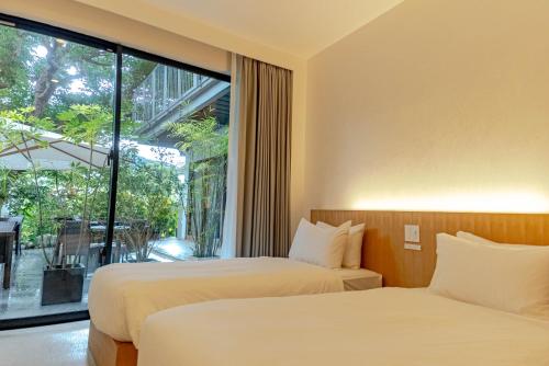 two beds in a room with a large window at kānusuba zamami in Zamami