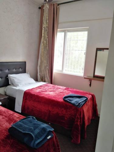 ein Schlafzimmer mit zwei Betten mit roter Bettwäsche und einem Fenster in der Unterkunft Al Midan Hotel in Amman