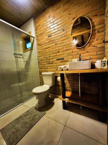 a bathroom with a toilet and a sink and a mirror at Cabanas Vista da Pedra in Grão Pará
