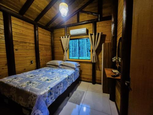 a small bedroom with a bed and a window at Cabanas Vista da Pedra in Grão Pará