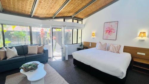 a bedroom with a bed and a blue couch at Hibiscus Villa - Beachfront, 2 pools, Tennis, Restaurant in Kororo Basin