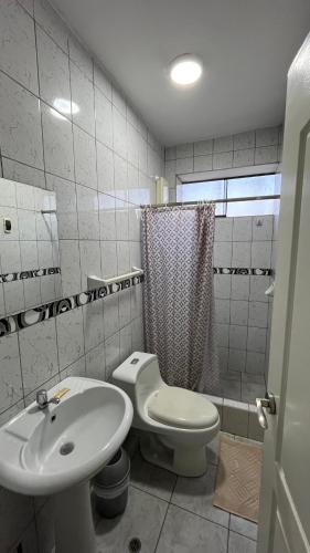 a bathroom with a white toilet and a sink at Hostal Bali - Talara in Talara