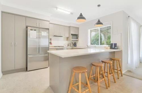 a kitchen with white cabinets and a counter with stools at Prime on Piper in Bathurst