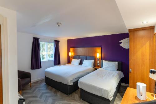 two beds in a hotel room with purple walls at Mundy Arms Hotel Derby in Derby