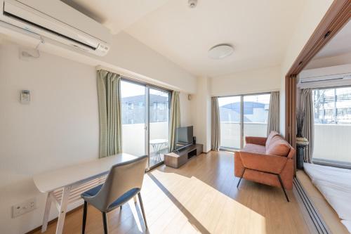 a living room with a desk and chairs and a couch at Jintai House401 in Hakata