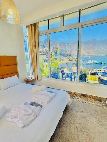 a bedroom with a bed and a large window at TIBERIAS by luxury Atitlan in San Pedro La Laguna