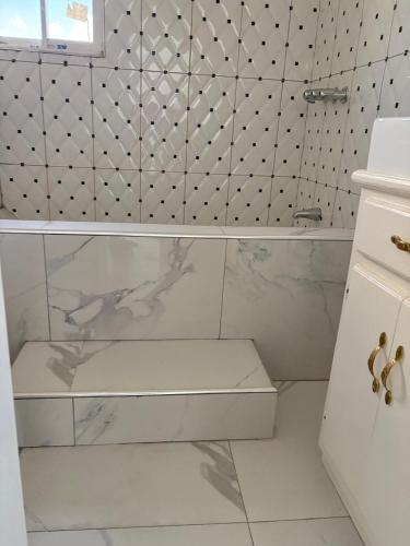 a white bathroom with a tub and a tile wall at VIP Hotel Haiti in Port-de-Paix