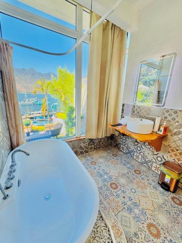 a bathroom with a tub and a large window at TIBERIAS by luxury Atitlan in San Pedro La Laguna