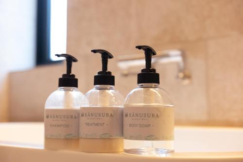 three bottles of soap sitting on a bathroom sink at kānusuba zamami in Zamami