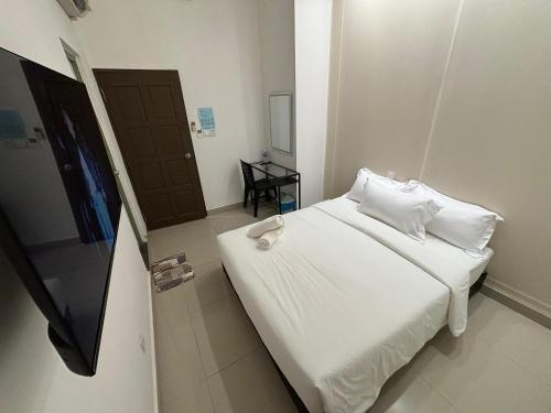 a bedroom with a bed with white sheets and pillows at One Point Hotel @ Airport (Kuching) in Kuching