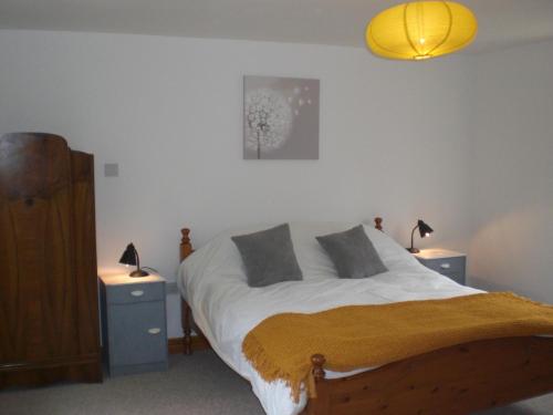 a bedroom with a bed with two night stands and two lamps at Bluebell and Appletree Cottages in Hockwold cum Wilton