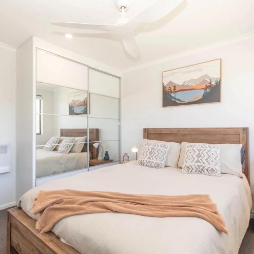 a bedroom with a large bed and a mirror at Lakeside Breeze in Jindabyne