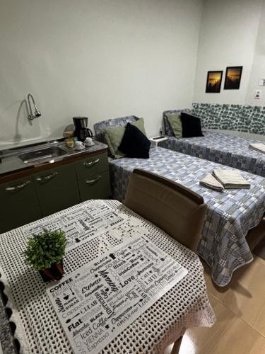 a room with two beds and a table and a kitchen at Rancho do Viajante Quarto B2 in Castro