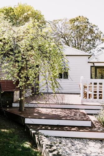 a house with a bench and a tree on a deck at Old Maffra Cottage in Maffra