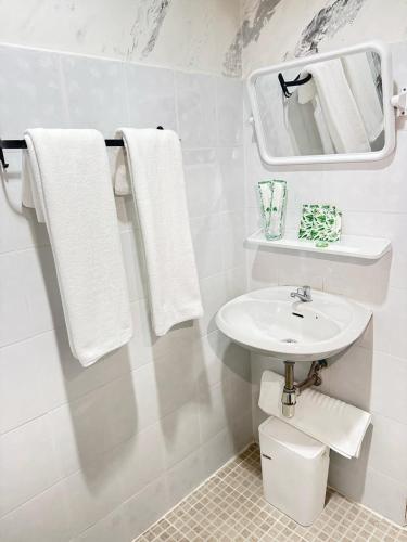 a white bathroom with a sink and a mirror at Top Residence Patong in Patong Beach