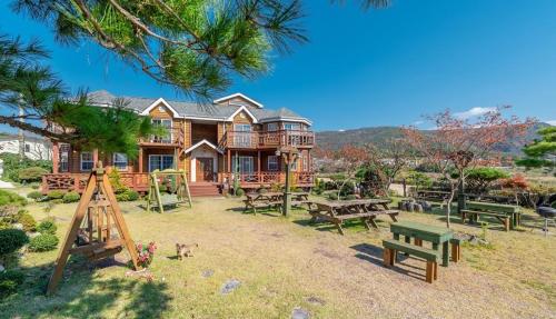 a log house with picnic tables and benches in the yard at Buan Pension Maple in Buan