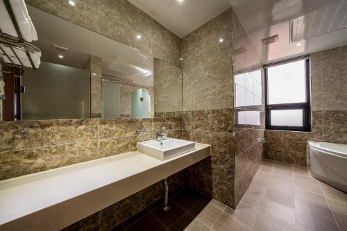 a bathroom with a sink and a tub and a mirror at Sunrise Hotel Seongsan in Seogwipo
