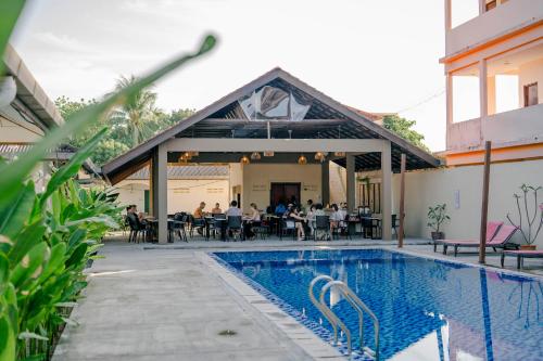 a group of people sitting around a table by a pool at Telaga Village Resort in Pantai Cenang