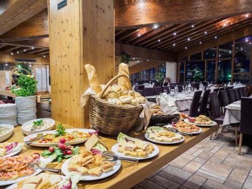 a long table with plates of food on it at Hotel Piandineve in Passo del Tonale