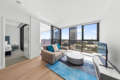 a living room with a couch and floor to ceiling windows at Yves Mermaid Beach Apartments by CLLIX in Gold Coast