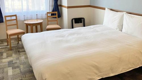 a bedroom with a large white bed and chairs at Toyoko Inn Toyama eki Shinkansen guchi No 1 in Toyama