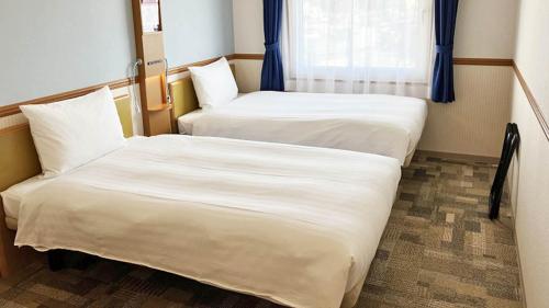 two beds in a small room with a window at Toyoko Inn Toyama eki Shinkansen guchi No 1 in Toyama