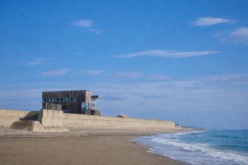 a building on the beach next to the ocean at 鹿島サーフヴィラ in Iijima
