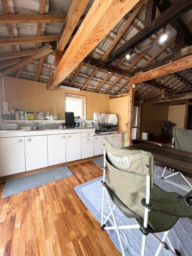 a kitchen with white cabinets and a chair in it at Kukaru クカル 伊平屋島の古民家一棟貸し in Gakiya