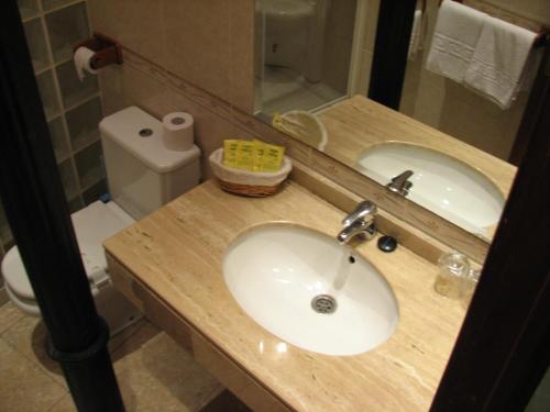 a bathroom with a sink and a mirror and a toilet at Hotel Nacional Melilla in Melilla