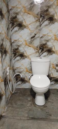 a bathroom with a white toilet in a stone wall at Pavis guest inn in Nallathanniya