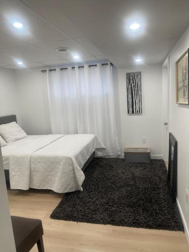 a bedroom with a white bed and a black rug at Ubbies place in Regina