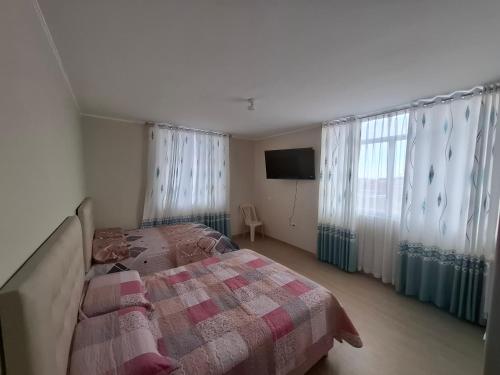 a bedroom with a bed and a tv and windows at Miski Wasi in Tacna