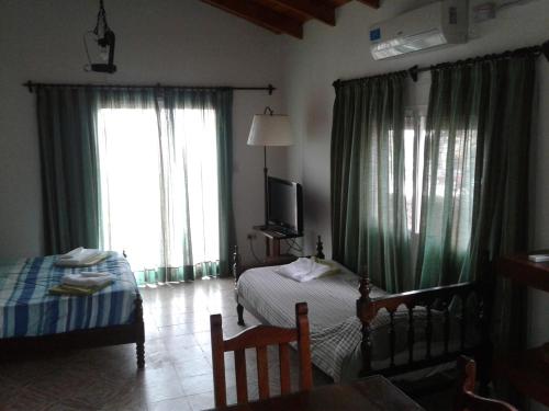 a bedroom with two beds and a tv and windows at Cedro Azul in Monte Hermoso