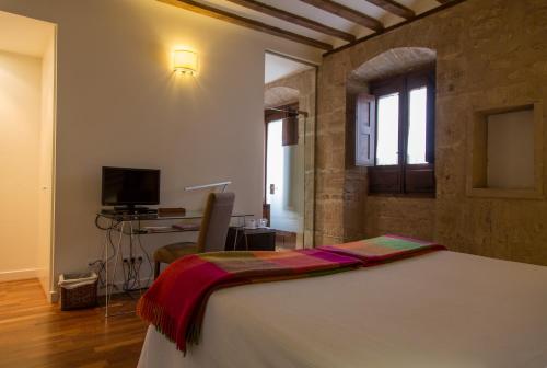 a bedroom with a bed and a desk and a television at La Capellanía in San Asensio