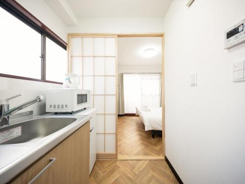 a kitchen with a sink and a microwave at Fuukanto Kinshicho BNB in Tokyo