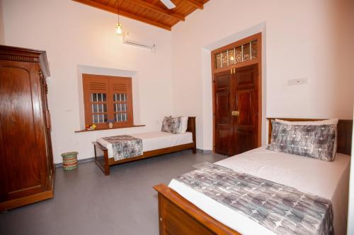 a bedroom with two beds and a chair in it at Cinnamon Legacy in Weligama