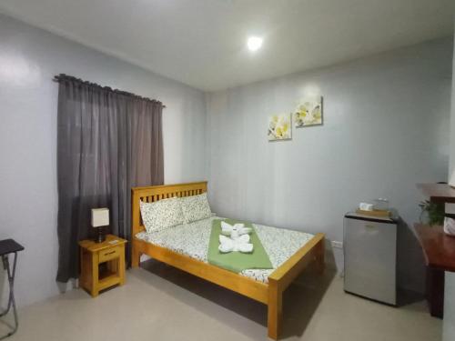a small bedroom with a bed and a refrigerator at Grae’s Apartelle in Moalboal
