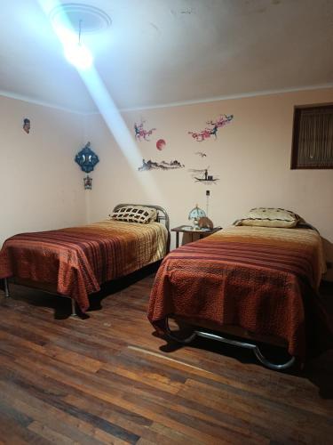 a bedroom with two beds and a light on the wall at Casa Magnolia in Cochabamba