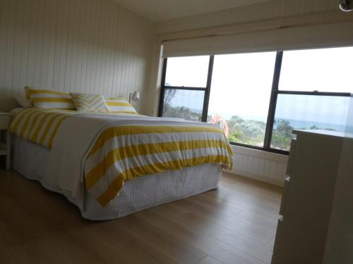 a bedroom with a bed with yellow and yellow stripes at Absolute beach front stunning views day and night in Cape Bridgewater