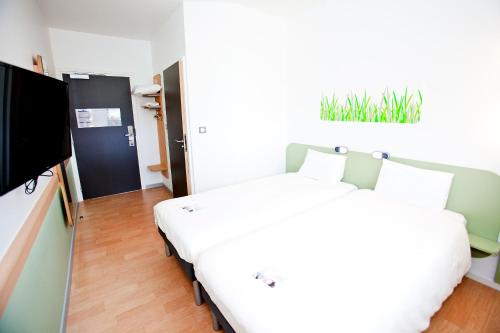 a bedroom with a bed and a flat screen tv at Ibis Budget Sarrebourg Buhl in Sarrebourg