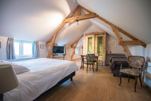 um quarto com uma cama e uma secretária num sótão em B&B Le Vieux Marronnier em Foy-Notre-Dame