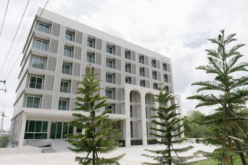 a white building with trees in front of it at M Hotel Kanchanaburi in Ban Chuk Kum