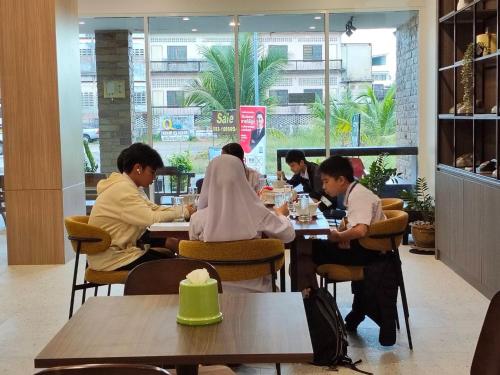 a group of people sitting at tables in a restaurant at S2S Queen Trang Hotel in Trang