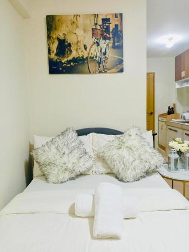 a white bed with fur pillows on top of it at Norman Condominium Unit Rental in Dumaguete