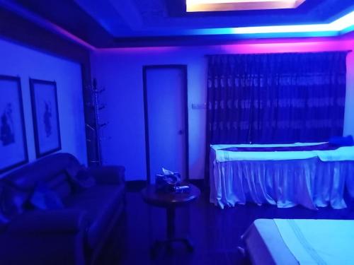 Dhaka Spa في داكا: غرفة بها أريكة وسرير مع أضواء أرجوانية