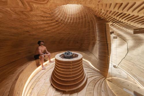 a man sitting on a circular wooden tunnel at Sanamane in Naoshima