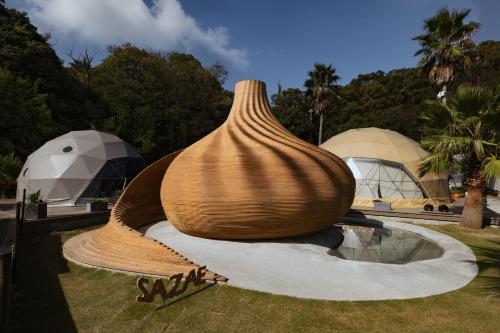 a large wooden vase sitting on the grass at Sanamane in Naoshima