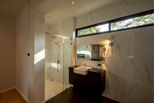 a bathroom with a shower and a sink and a mirror at Cicada Estate in Ban Mae Pu Kha
